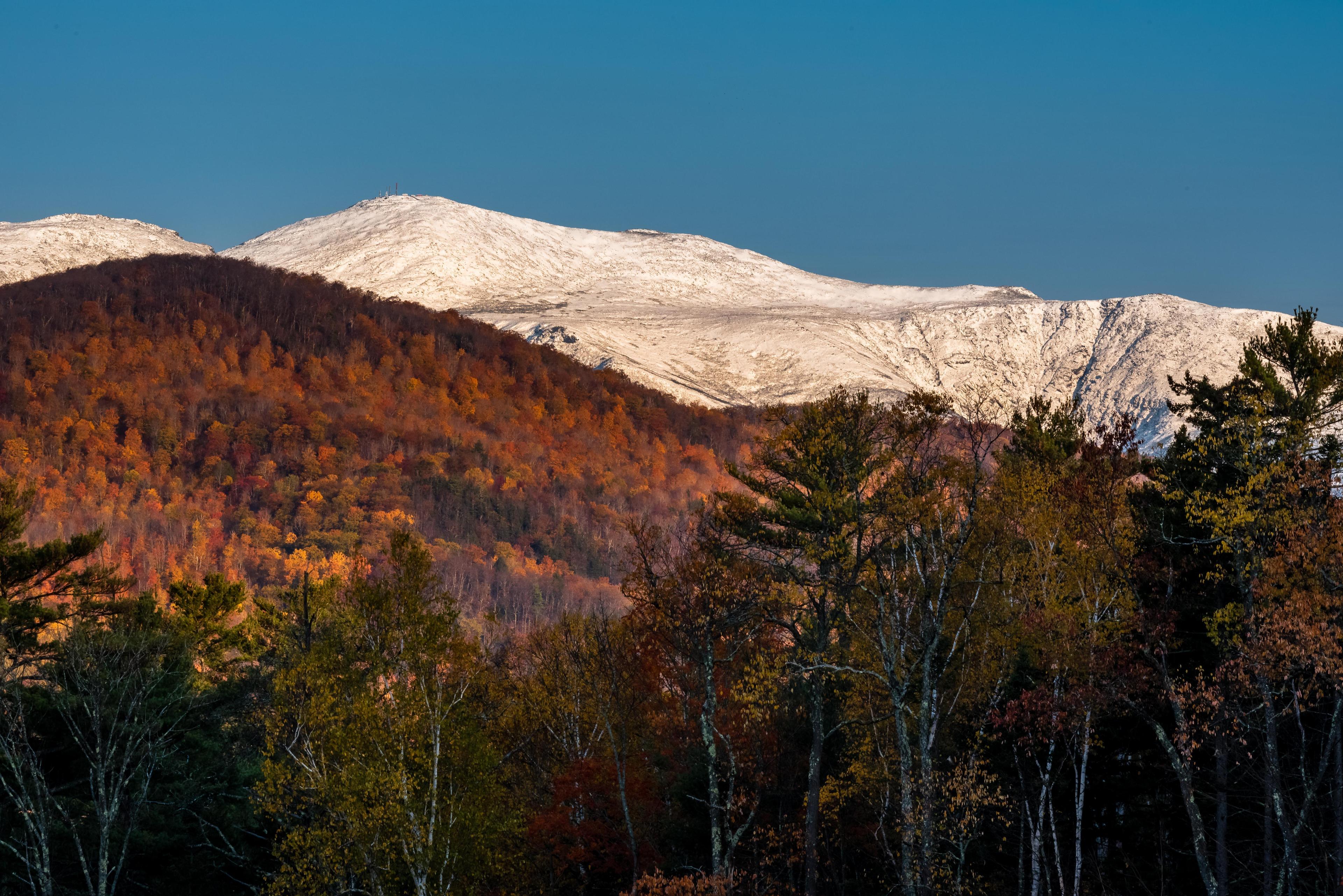 Foliage in the mountains with a snow-covered Mount Washington in the background. Foliage in the mountains with a snow-covered Mount Washington in the background.